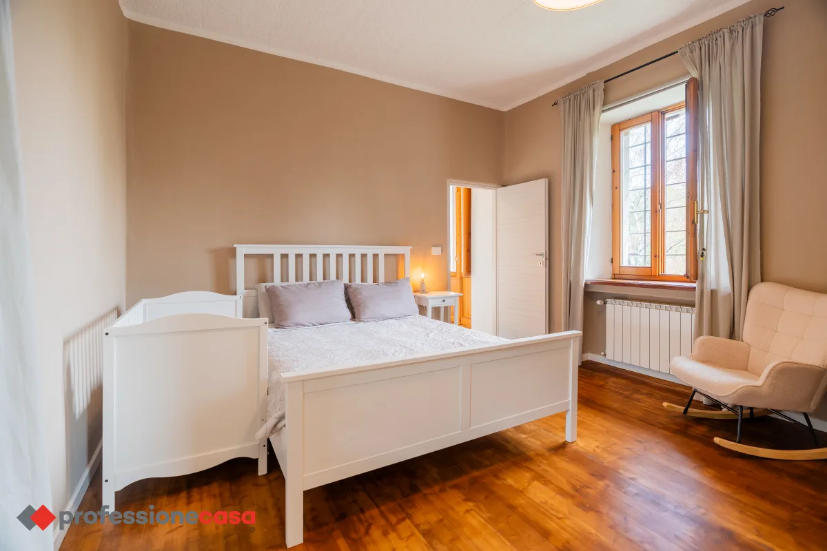 Camera da letto luminosa in una villa a Cantalupa, con letto bianco e pavimento in parquet